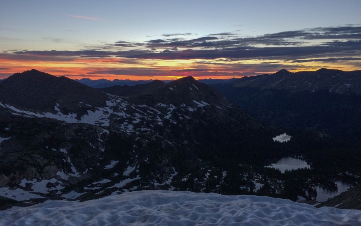 the sun is rising, illuminating snowy mountains at dawn